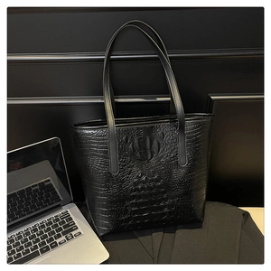 Close-up of black crocodile embossed tote bag texture with sleek shoulder straps
