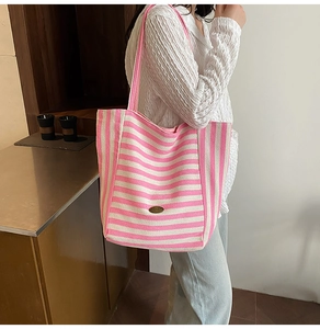 Detail of pink and white striped canvas tote bag showing stitching and metal emblem