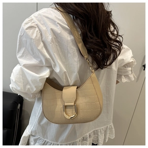 Detail of beige crocodile pattern hobo bag with a gold horseshoe buckle on a model