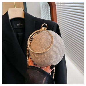 Close-up of golden spherical evening bag with rhinestone-encrusted ring handle and chain