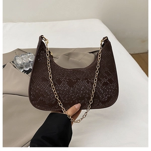 Dettaglio texture serpente marrone scuro e catena dorata sulla borsa a mezzaluna