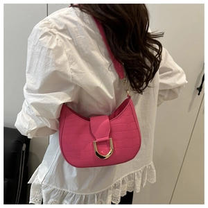 Dettaglio borsa a mezzaluna fucsia con trama coccodrillo e chiusura a ferro di cavallo