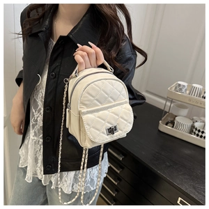 Close-up of a white quilted mini backpack with a gold chain strap and metal turn-lock