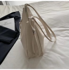 Detail of adjustable shoulder strap and silver metal hardware on a cream tote bag