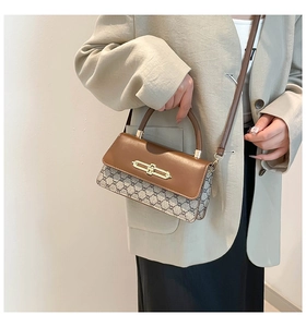 Close-up of vintage brown leather flap and golden lock on monogram shoulder bag