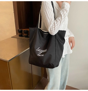 Close-up of black oversized nylon tote bag with white artistic lettering for daily use