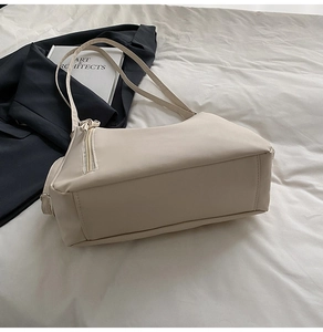 Detail of minimalist beige leather tote with top zipper and slim shoulder strap