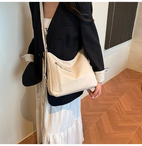 Detail of off-white crescent crossbody bag with decorative zipper and long tassels