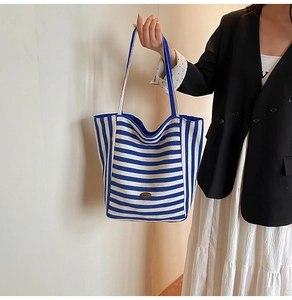 Detail of blue and white striped tote bag with high-capacity design and metal logo plate