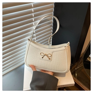 Detail of white crocodile texture leather bag with a golden bow metal buckle