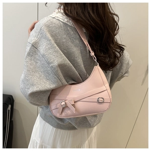 Detail of pink half-moon shoulder bag with cross straps and silver metal buckles