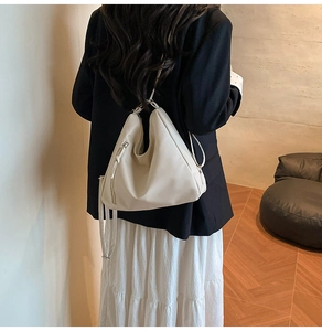 Adjustable shoulder strap and side zipper detail of a cream-colored soft leather hobo bag