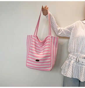 Close-up of pink striped canvas tote bag with long shoulder straps and oval logo label