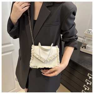 Détail du sac bandoulière blanc à franges avec un design de pompons bohème