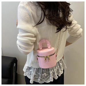 Sac seau cylindrique rose avec chaîne dorée porté en bandoulière sur un mannequin