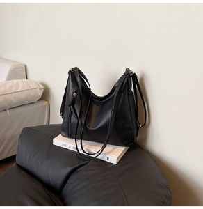 Detail of black faux leather tote bag with vertical zipper pocket on white books