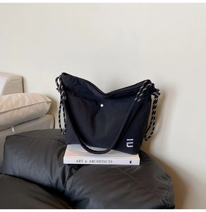 Détail du sac cabas en nylon noir avec bandoulière tressée et fermoir métallique