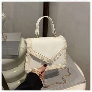 Détail du sac à main en cuir blanc avec rabat en V, franges denses et chaîne dorée