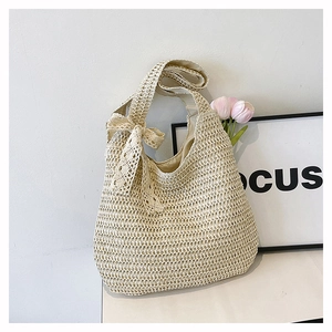 Detail of woven hobo bag with a decorative lace bow and natural straw texture