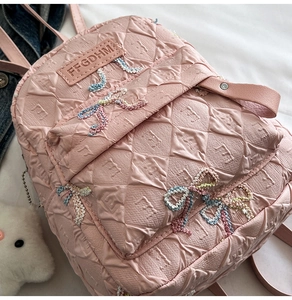 Detailed macro view of pink quilted texture fabric and woven bows on a stylish backpack