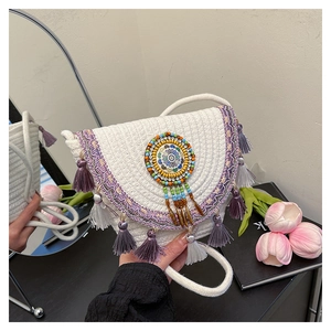 Detail of bohemian white woven saddle bag featuring purple fringe and ethnic embroidery