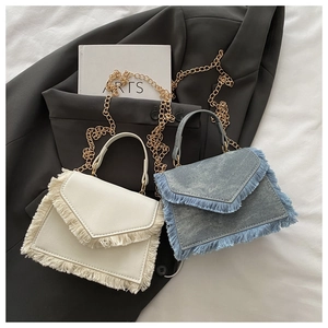 Détail de sacs bandoulière à franges denim et beige avec chaînes dorées sur blazer