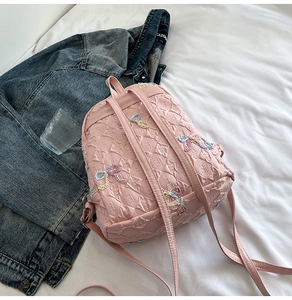 Detailed close-up of pink mini backpack with embossed texture and colorful bow embroidery