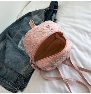 Detailed interior of pink diamond-pattern backpack with floral embroidery and zipper