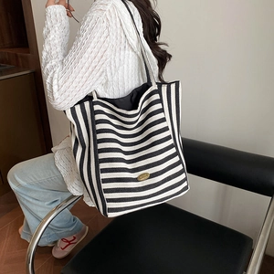 Large black and white striped canvas tote bag with gold logo and black shoulder straps