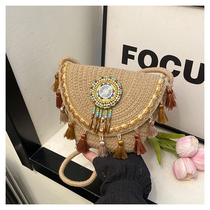 Détail du sac de selle en paille bohème avec glands multicolores et perle mandala