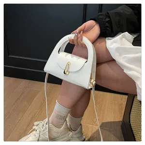 Close-up of a white minimalist handbag featuring a unique gold geometric metal buckle