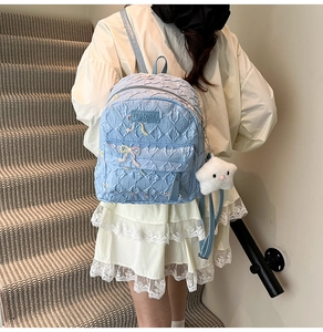 Detail view of light blue backpack featuring embossed texture and cute bow embroidery