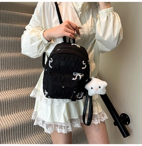Close-up of black quilted mini backpack featuring colorful bow embroidery and star charm