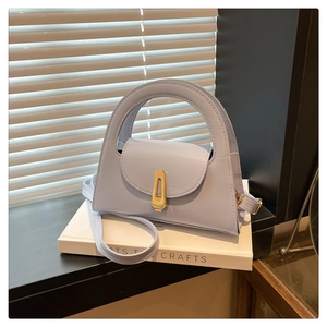 Detailed view of light blue leather handbag with golden buckle and sleek arc handle