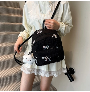 Close-up of black mini backpack with colorful bow embroidery and star plush pendant