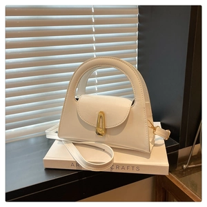 Macro shot of white semi-circle handbag featuring a golden shield lock and smooth PU texture