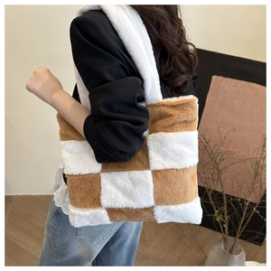 Gros plan du sac cabas en peluche à damier marron et blanc porté sur un manteau noir
