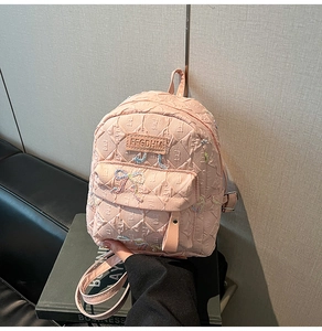 Detailed view of pink quilted mini backpack with colorful bow patterns and logo plate