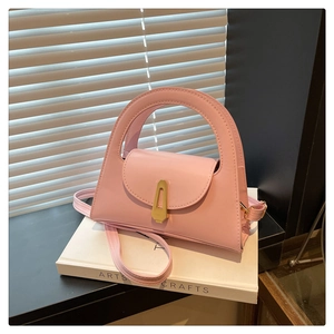 Detail of light pink leather handbag showing elegant geometric gold metal lock and handle
