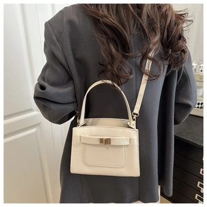 Detailed side view of off-white textured leather crossbody bag with gold twist lock buckle