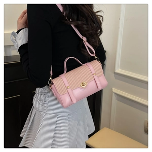 Detail of pink leather handbag with woven flap and golden metal clasp on a model