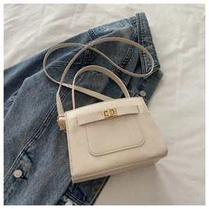 Detail of cream square crossbody bag with Saffiano texture and golden turn-lock closure