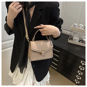 Detail of cream square handbag with gold twist lock and elegant top handle