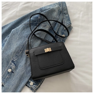 Detail view of black Saffiano leather crossbody bag with gold twist lock on denim jacket