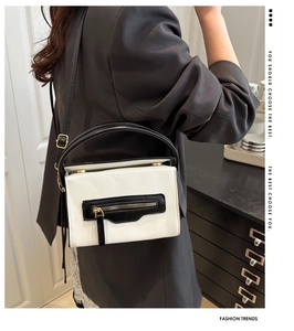 Dettaglio della borsa quadrata in bianco e nero con zip in metallo e finiture dorate