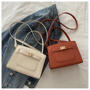 Detail of elegant cream and brick red square bags with golden turn-lock fasteners