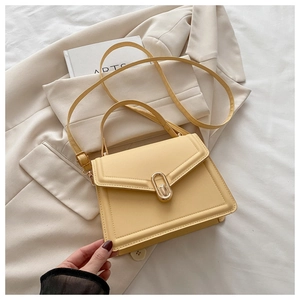 Détail du sac à main en cuir jaune clair avec fermoir doré sur un costume élégant