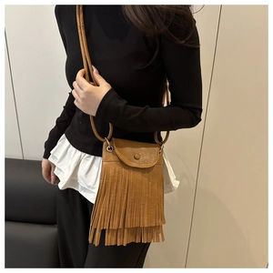 Petit sac bandoulière en cuir marron avec détails de franges porté par un modèle