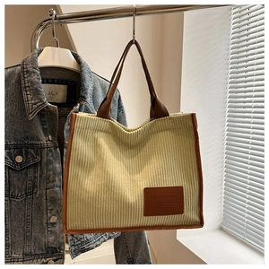 Detail der grünen Cord-Tasche mit braunen Kontrastgriffen und Mode-Label