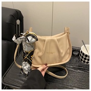 Dettaglio della borsa a nuvola beige plissettata con foulard di seta e logo dorato